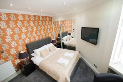 a bedroom with a bed and a tv on a wall at Palmerston Suites in Edinburgh