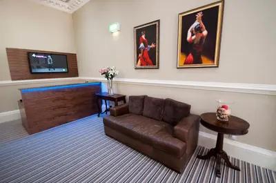 a living room with a couch and a flat screen tv at Palmerston Suites in Edinburgh