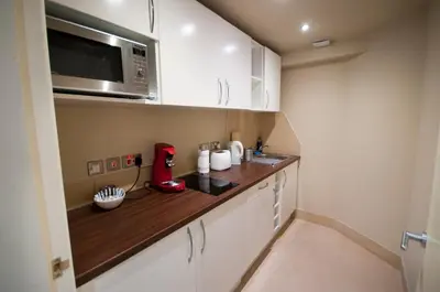 a small kitchen with white cabinets and a microwave at Palmerston Suites in Edinburgh