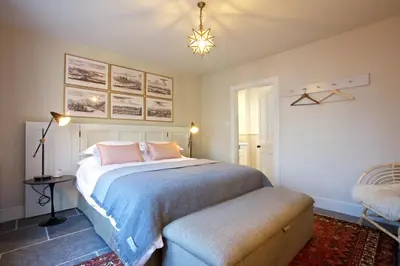 a bedroom with a large bed and a chair at Ross Lodge in Comrie