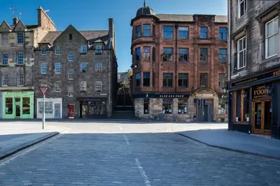 an empty street in a city with tall buildings at Castle Vista, Grassmarket Apartment in Edinburgh