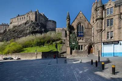 an old building with a castle in the background at Castle Vista, Grassmarket Apartment in Edinburgh