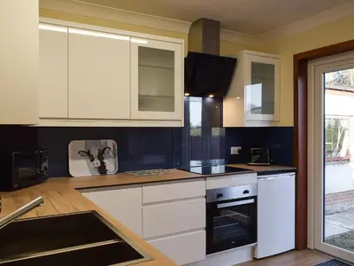 a kitchen with white cabinets and a stove top oven at The Hoolit in Crieff