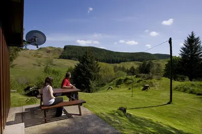two people sitting on a bench looking at a field at Lagnakeil Highland Lodges in Oban