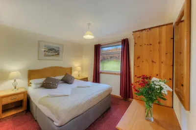 a bedroom with a bed and a vase of flowers on a table at Lagnakeil Highland Lodges in Oban