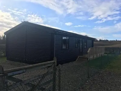 a small black shed with a wooden fence at Concraig Lodge in Crieff