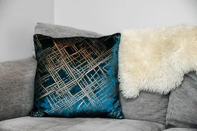 a pillow sitting on top of a gray couch at Rowan Tree Apartment - Modern Apartment, Free Parking & Views in Oban
