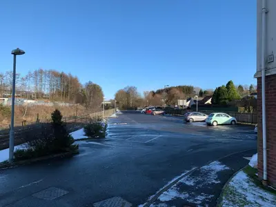 an empty parking lot with cars parked in it at Flat One, 212 Eaglesham Road, East Kilbride, Glasgow in Glasgow