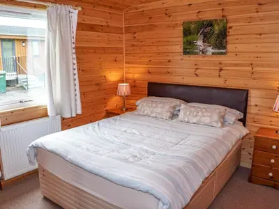 a bedroom with a bed in a wooden wall at Chalet Osprey Lodge by Interhome in Kinross