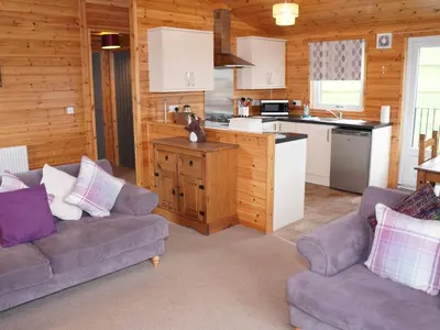a living room with two couches and a kitchen at Chalet Osprey Lodge by Interhome in Kinross