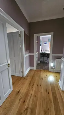 an empty room with a wooden floor and two doors at Beautiful self contained apartment with garden in Glasgow