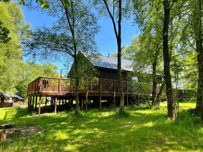 a log cabin in the middle of a field with trees at Fern Lodge in Dalavich