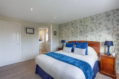 a bedroom with a large bed with blue and white pillows at 45 Guthrie Court, Fantastic top floor apartment next to Gleneagles in Auchterarder
