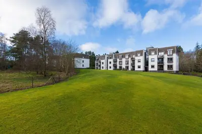 a large grassy field in front of a building at 45 Guthrie Court, Fantastic top floor apartment next to Gleneagles in Auchterarder