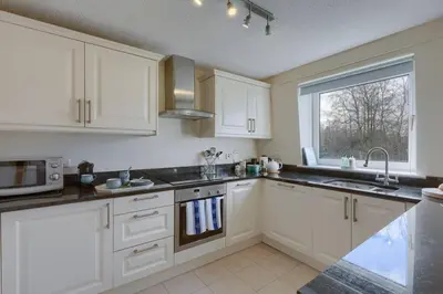 a kitchen with white cabinets and a sink and a window at 45 Guthrie Court, Fantastic top floor apartment next to Gleneagles in Auchterarder