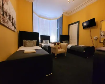 a hotel room with three beds and a chair at Stay - Gilmore Guesthouse in Edinburgh