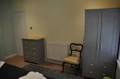 a bedroom with a bed and a chair and a dresser at Arrochoile Cottage in Glasgow