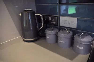 a kitchen counter with a coffee pot and four cans at Arrochoile Cottage in Glasgow