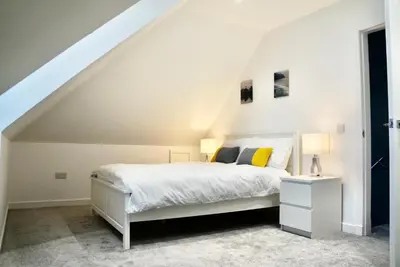 a white bedroom with a white bed and a staircase at Leworin in Stirling