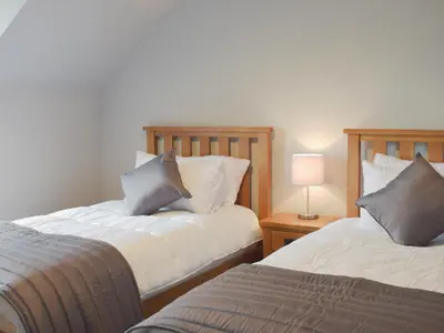 a bedroom with two beds and a table with a lamp at The School House in New Luce