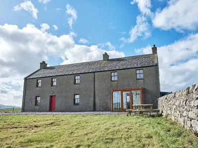 a large stone building with a bench in front of it at Midcraigs in Kilchenzie