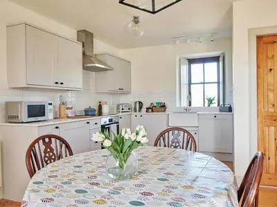 a kitchen with a table with a vase of flowers on it at Midcraigs in Kilchenzie
