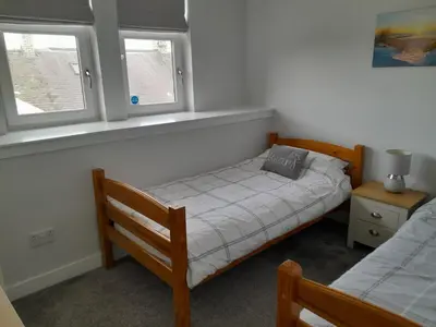 a small bedroom with a bed and two windows at Meadowbank in Girvan