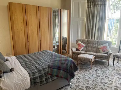 a bedroom with a bed and a couch and a chair at Dellwood Hotel in Campbeltown