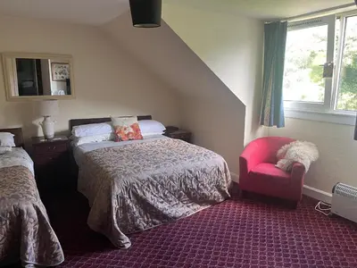 a bedroom with a bed and a red chair at Dellwood Hotel in Campbeltown