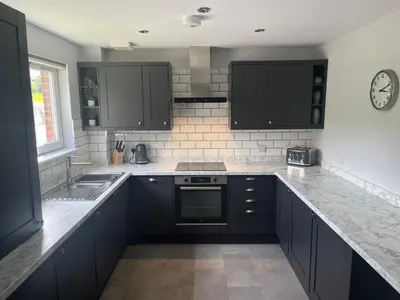 a kitchen with black cabinets and a counter top at Flat Two, 212 Eaglesham Road, East Kilbride, Glasgow in Glasgow