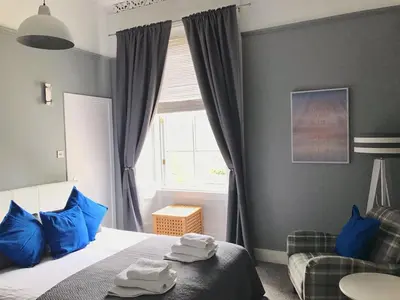 a bedroom with a bed and a window with blue pillows at Bishopton Apartment, near Glasgow in Bishopton