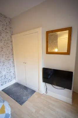 a bedroom with a television and a mirror on the wall at Sandgate 2-Bed Apartment in Ayr central location in Ayr
