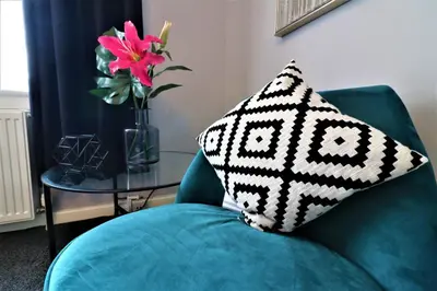 a pillow on a green chair with a vase of flowers at Signature - Carfin House in Carfin