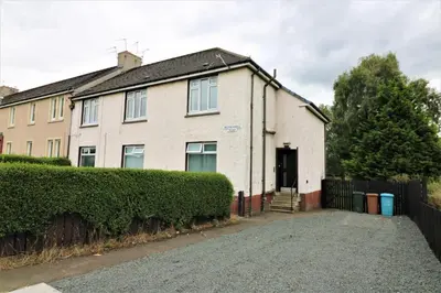 a white house with a fence and a driveway at Signature - Carfin House in Carfin
