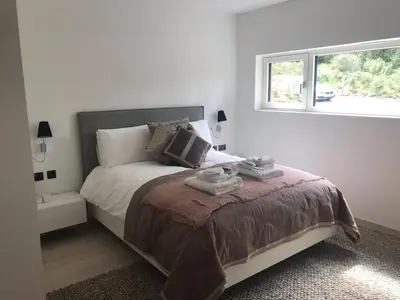 a white bedroom with a bed with a window at Red Stag with stunning loch and waterfall view in Crianlarich