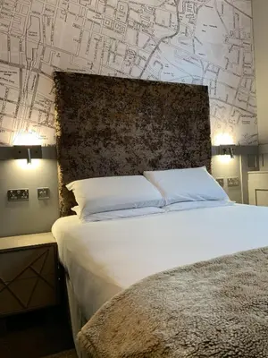 a bedroom with a bed and a wall with drawings on it at Babbity Bowsters in Glasgow