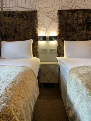 a room with two beds and a wall with drawings at Babbity Bowsters in Glasgow