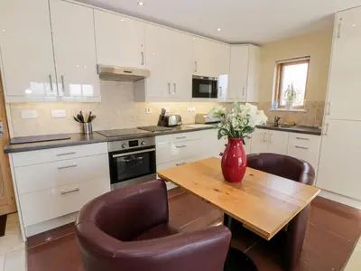 a kitchen with a wooden table with a vase of flowers on it at Ettrick Cottage in Port Bannatyne