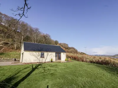 a small white house with a large grass yard at Ettrick Cottage in Port Bannatyne