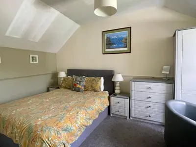 a bedroom with a bed and a dresser with a night stand at TwoStones Self Catering Cottage in Arrochar