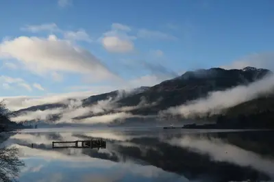 a body of water with a reflection of a mountain at TwoStones Self Catering Cottage in Arrochar