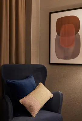a blue chair with a pillow in a room at voco Edinburgh - Haymarket by IHG in Edinburgh