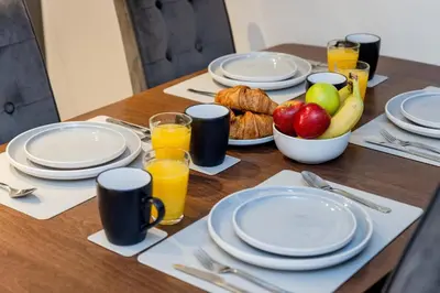 a table with plates and fruit and glasses of orange juice at Dragon Suites - Edinburgh City Centre 2 Bed Apartment in Edinburgh