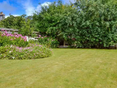 a garden with pink flowers and a large tree at Culpee House in Newton Stewart