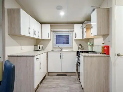 a small kitchen with white cabinets and a sink at The Paddocks - Uk7112 in Alloa