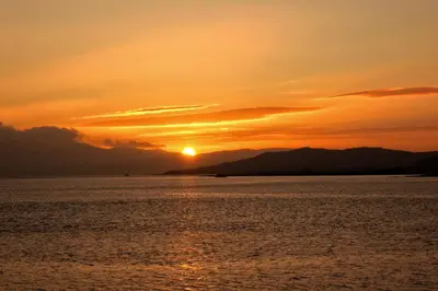 a sunset over a body of water with the sun setting at FSC Millport Hostel in Millport
