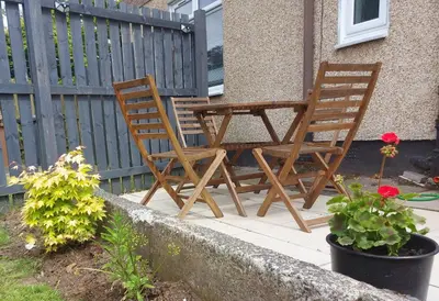 two chairs and a table on a patio with flowers at LAWFIELD R&R in West Kilbride