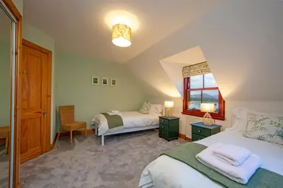 a bedroom with two beds and a window at Seabank Lochside Farmhouse in Oban
