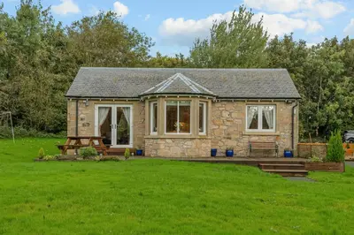 a stone cottage with a picnic table in a yard at The Ploughman's Poet in Bathgate