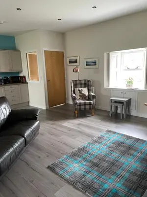a living room with a couch and a chair and a table at Ben Lomond Cottage in Gartocharn